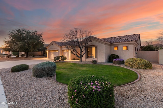 mediterranean / spanish-style home with concrete driveway, a tile roof, an attached garage, fence, and stucco siding