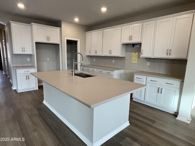 kitchen with a kitchen island with sink, white cabinetry, dark wood-style flooring, and a sink