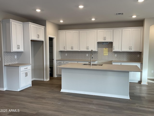 kitchen with white cabinetry, a center island with sink, visible vents, and a sink