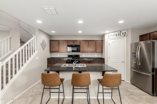 kitchen with sink, a kitchen breakfast bar, a kitchen island with sink, light tile patterned floors, and black appliances