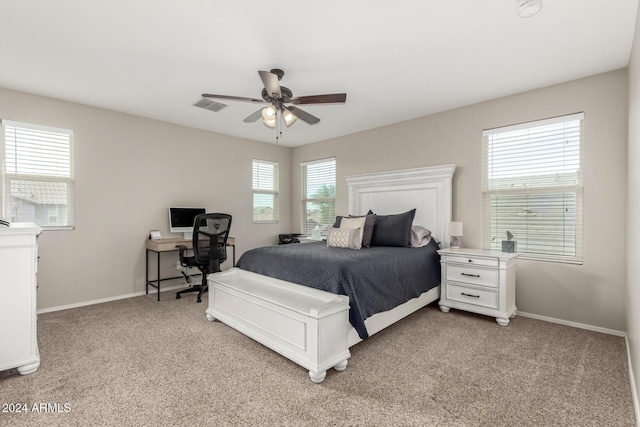 bedroom with multiple windows, ceiling fan, and light colored carpet