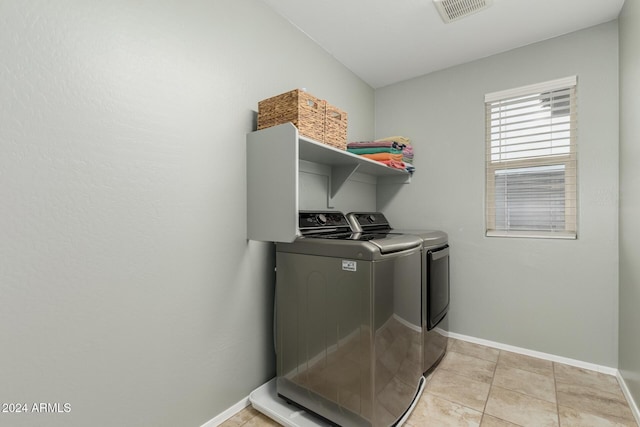 clothes washing area featuring light tile patterned flooring and separate washer and dryer