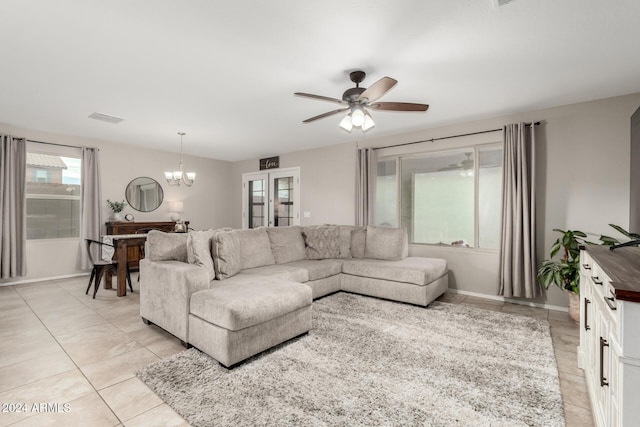 tiled living room with ceiling fan with notable chandelier