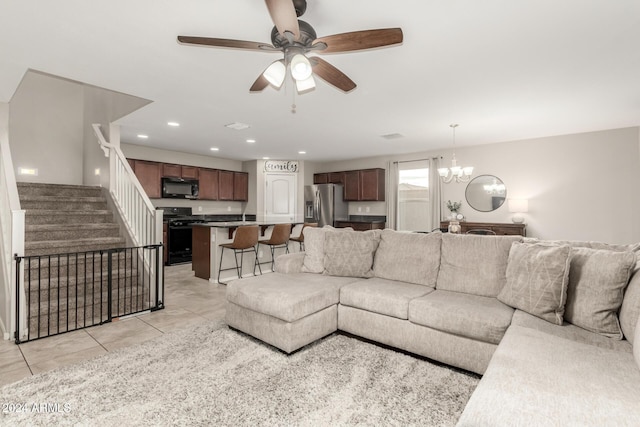 living room with ceiling fan with notable chandelier and light tile patterned floors