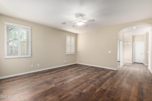 empty room featuring ceiling fan, plenty of natural light, and dark hardwood / wood-style flooring