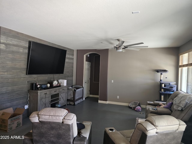 14604 W Banff Ln, Surprise, AZ 85379 - living area with an accent wall, a ceiling fan, wood walls, arched walkways, and baseboards