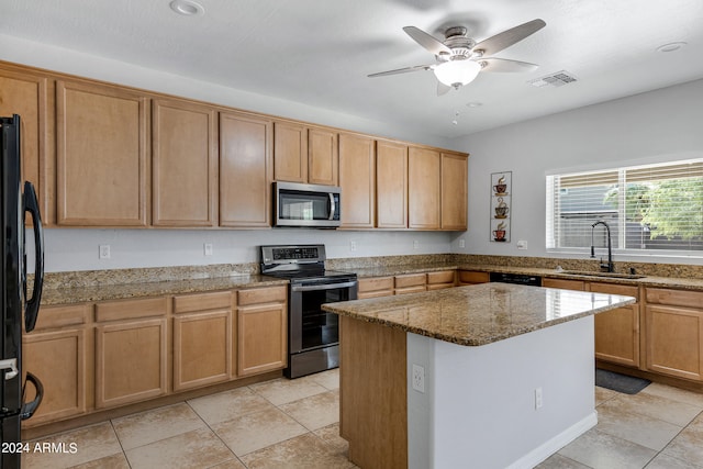 kitchen featuring light stone counters, sink, black appliances, ceiling fan, and a kitchen island