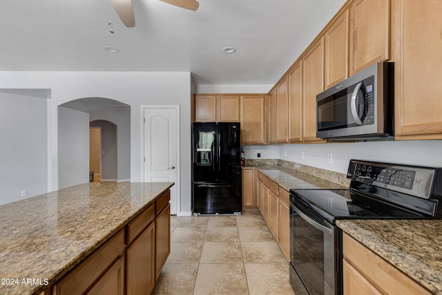 kitchen featuring light tile patterned floors, black appliances, ceiling fan, and light stone countertops