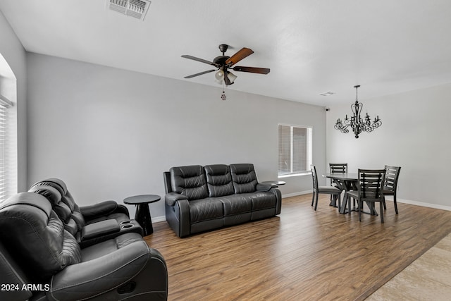 living room featuring ceiling fan with notable chandelier and light hardwood / wood-style floors