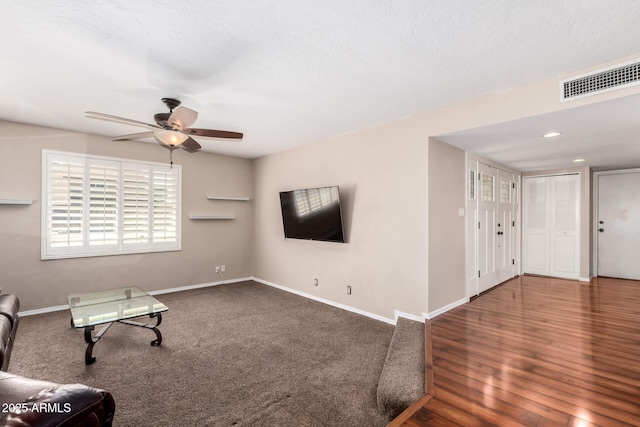 living area with visible vents, ceiling fan, baseboards, and wood finished floors