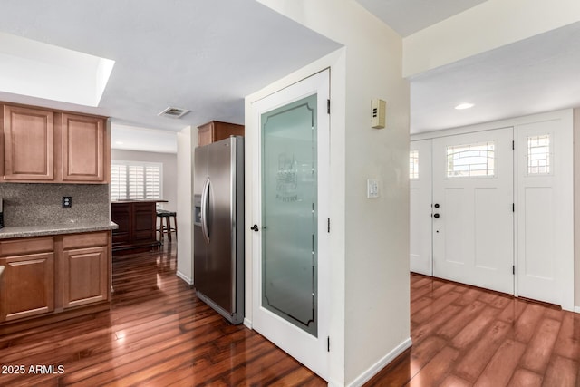 kitchen with visible vents, stainless steel refrigerator with ice dispenser, tasteful backsplash, baseboards, and dark wood-style flooring