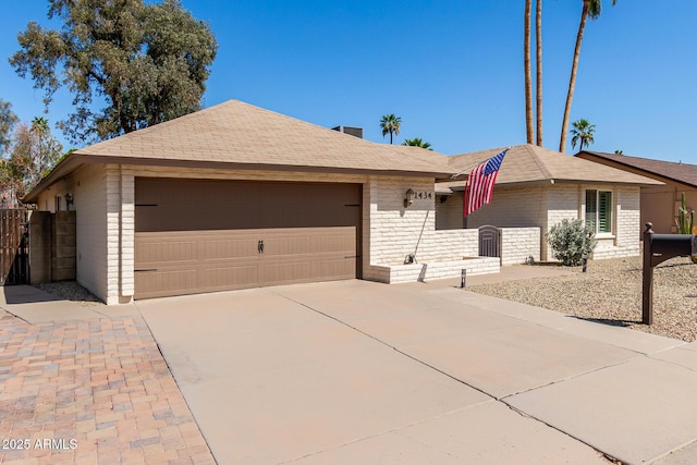 ranch-style house with concrete driveway, an attached garage, fence, and brick siding