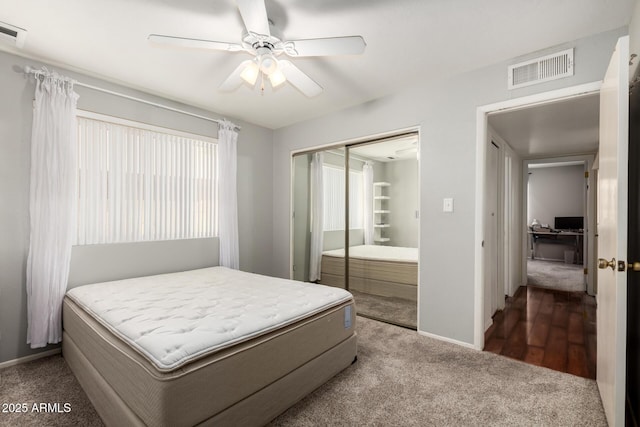 carpeted bedroom with a closet, visible vents, a ceiling fan, and baseboards