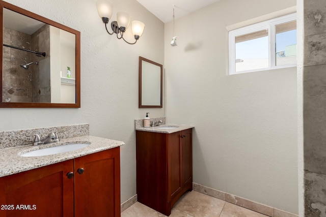 bathroom with a tile shower, tile patterned flooring, two vanities, and a sink