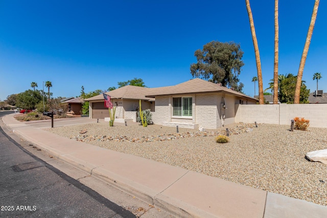 single story home featuring brick siding, an attached garage, and fence