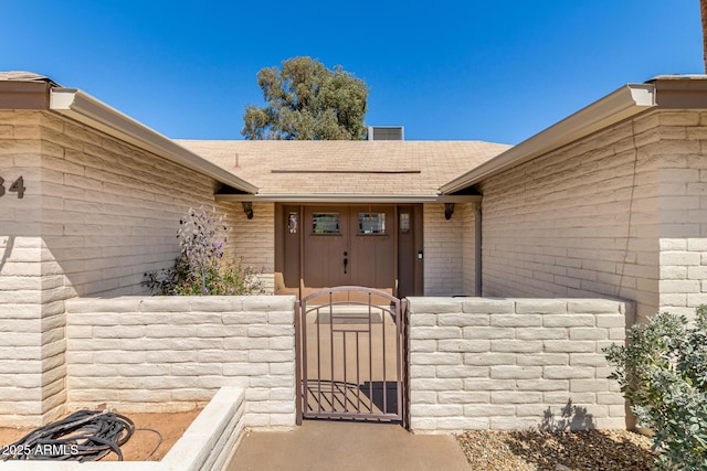 property entrance featuring roof with shingles and a gate
