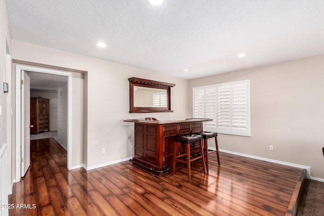 bar with recessed lighting, baseboards, a bar, and dark wood finished floors