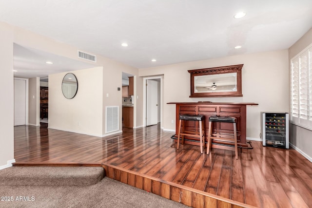 dining room with beverage cooler, visible vents, a dry bar, and wood finished floors