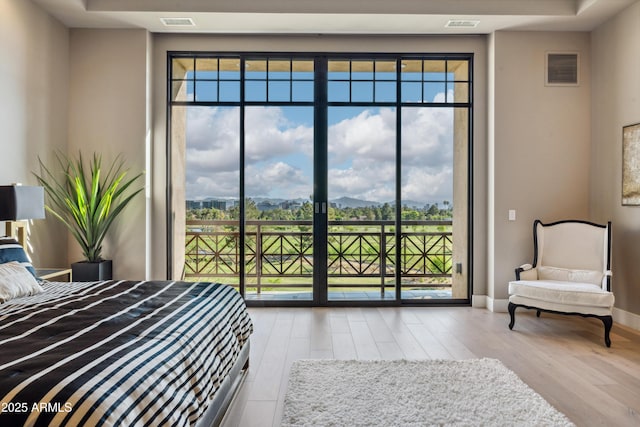 bedroom with access to outside, hardwood / wood-style floors, and baseboards