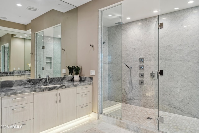 bathroom featuring marble look tile flooring, a marble finish shower, recessed lighting, and vanity