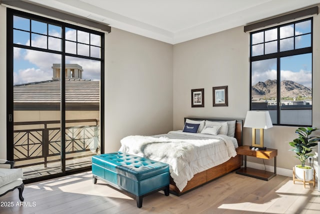bedroom featuring hardwood / wood-style floors, a mountain view, baseboards, and access to exterior