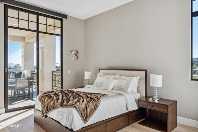 bedroom with access to exterior, wood finished floors, and baseboards