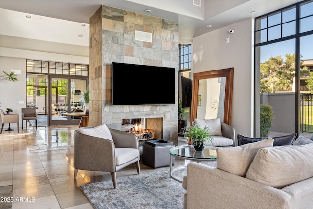 living area with a tile fireplace and a high ceiling