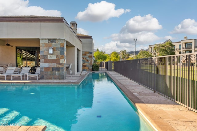 view of swimming pool featuring fence, a ceiling fan, and a patio area
