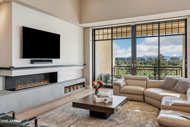 living room with a glass covered fireplace, wood finished floors, and french doors