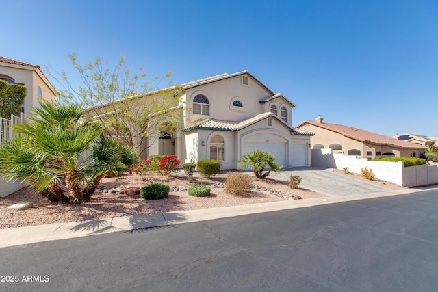 mediterranean / spanish home featuring an attached garage, fence, a tiled roof, decorative driveway, and stucco siding