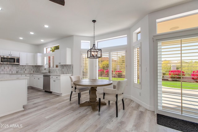 dining room featuring a chandelier, recessed lighting, baseboards, and light wood finished floors