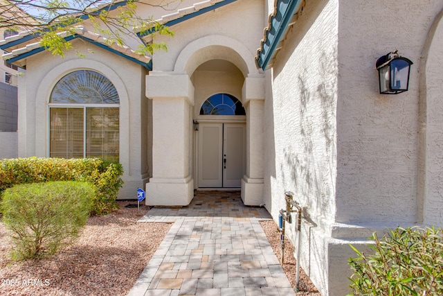 view of exterior entry featuring a tiled roof and stucco siding