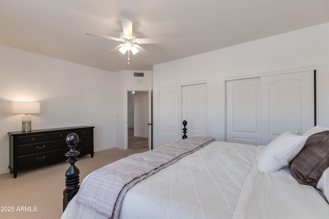 bedroom featuring light carpet, ceiling fan, two closets, and visible vents