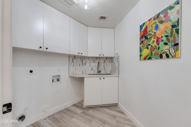 clothes washing area featuring light wood-style flooring, visible vents, a sink, and gas dryer hookup