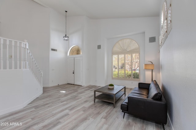 interior space with visible vents, stairway, wood finished floors, high vaulted ceiling, and baseboards