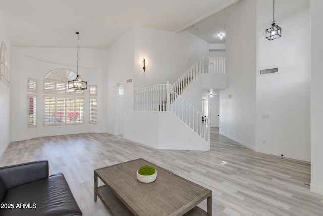 unfurnished living room with high vaulted ceiling, stairs, visible vents, and wood finished floors