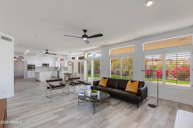 living area with light wood finished floors, baseboards, visible vents, and a ceiling fan