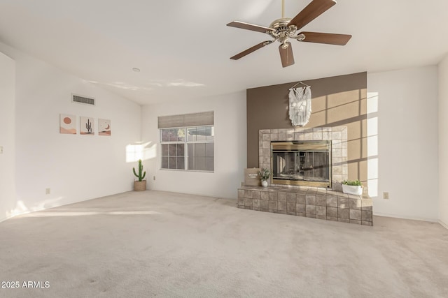 living area with visible vents, carpet flooring, vaulted ceiling, ceiling fan, and a tile fireplace