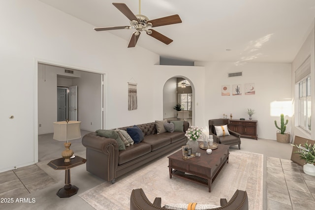 carpeted living room with arched walkways, ceiling fan, vaulted ceiling, and visible vents