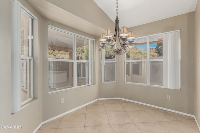 unfurnished dining area with a chandelier, vaulted ceiling, baseboards, and tile patterned floors