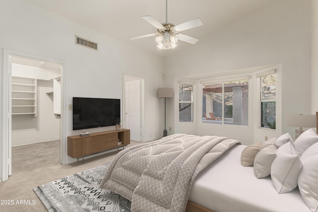 bedroom featuring light carpet, visible vents, a ceiling fan, a spacious closet, and vaulted ceiling