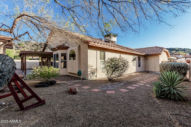 exterior space featuring a tile roof and stucco siding