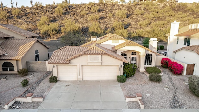 mediterranean / spanish home with an attached garage, fence, a tiled roof, concrete driveway, and stucco siding