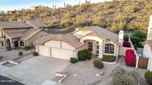 view of front of house featuring a tile roof, a chimney, stucco siding, an attached garage, and driveway