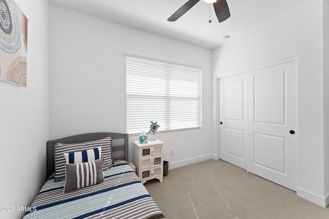 bedroom featuring light carpet, ceiling fan, a closet, and baseboards