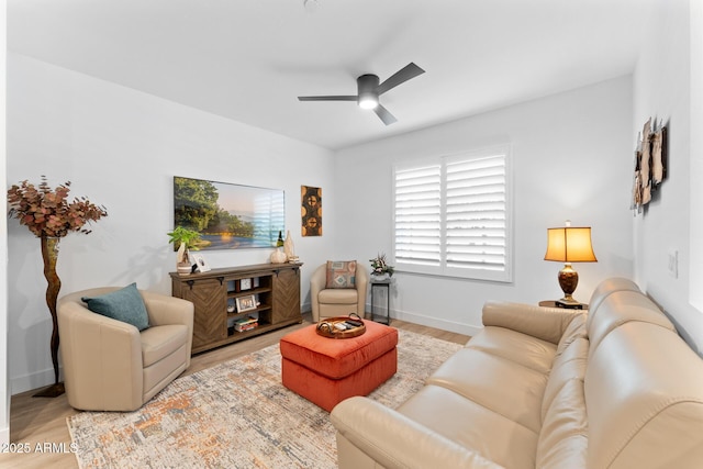 living room with light wood-style floors, ceiling fan, and baseboards