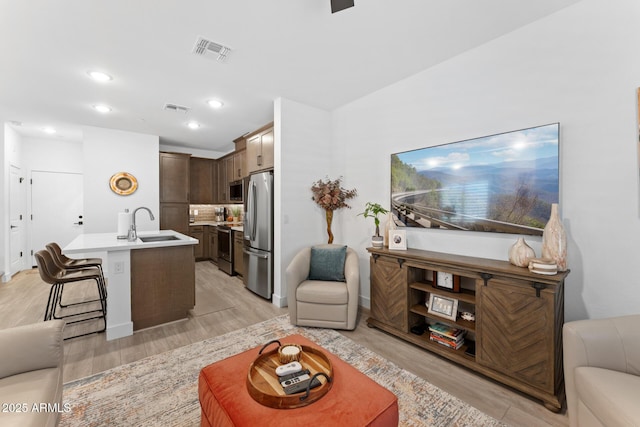 living room with light wood-type flooring, visible vents, and recessed lighting