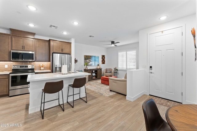 kitchen with visible vents, open floor plan, light countertops, appliances with stainless steel finishes, and a center island with sink