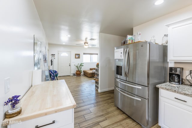 kitchen featuring ceiling fan, light stone counters, stainless steel fridge, light hardwood / wood-style floors, and white cabinets