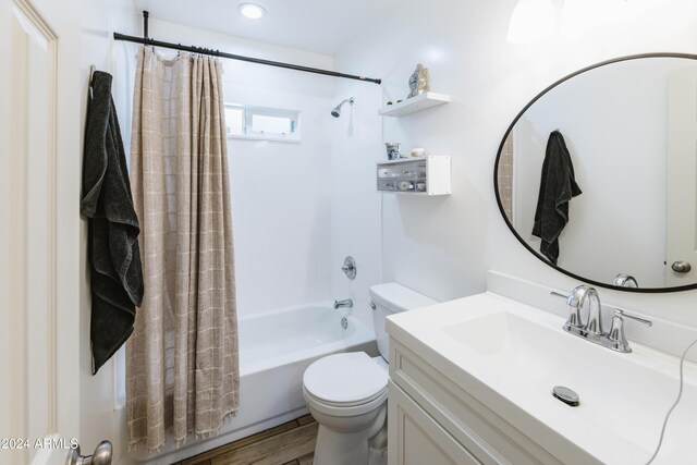 full bathroom featuring hardwood / wood-style floors, vanity, shower / tub combo, and toilet